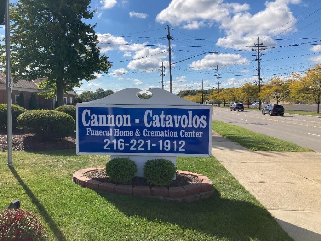 Sign for Cannon-Catavolos Funeral Home & Cremation Center. Phone number is visible. Blue sky, roadside setting.