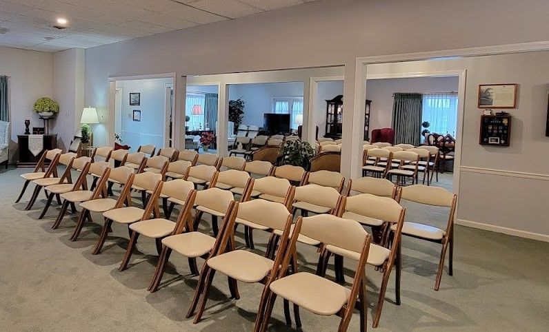 Rows of beige folding chairs set up in a room with doorways leading to other rooms, presumably for an event.