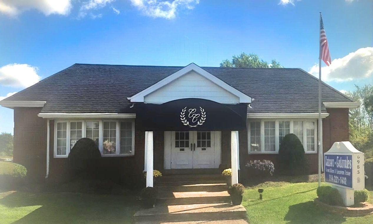 Brick building with a dark roof, American flag, and sign reading 