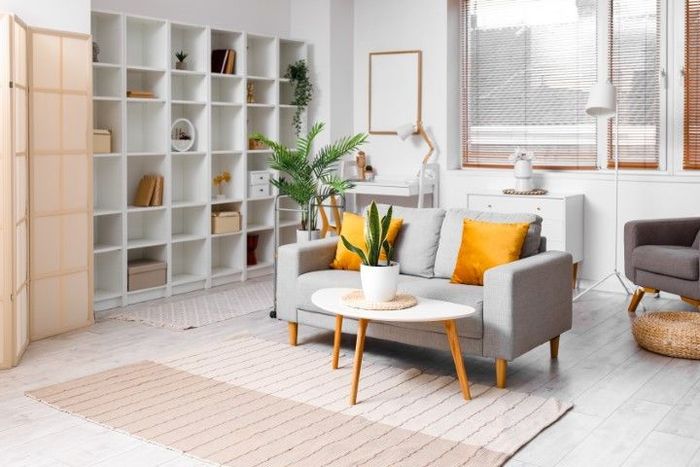 Living room with gray sofa, yellow pillows, white shelving, and natural light.