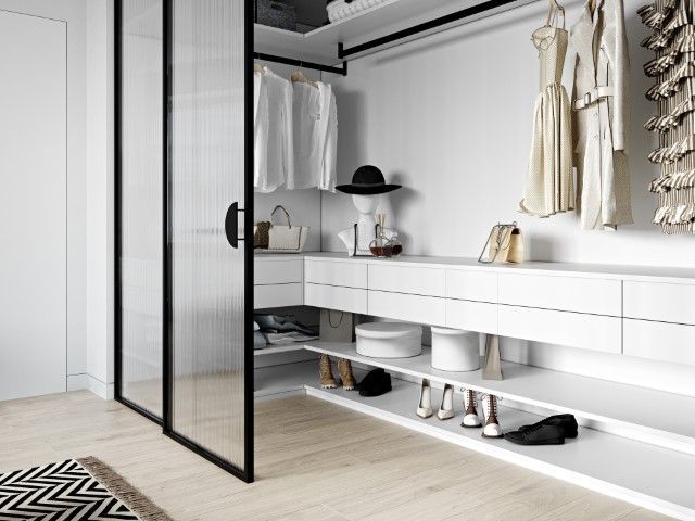 Modern white closet with glass doors, clothing, shoes, hat, and purses.