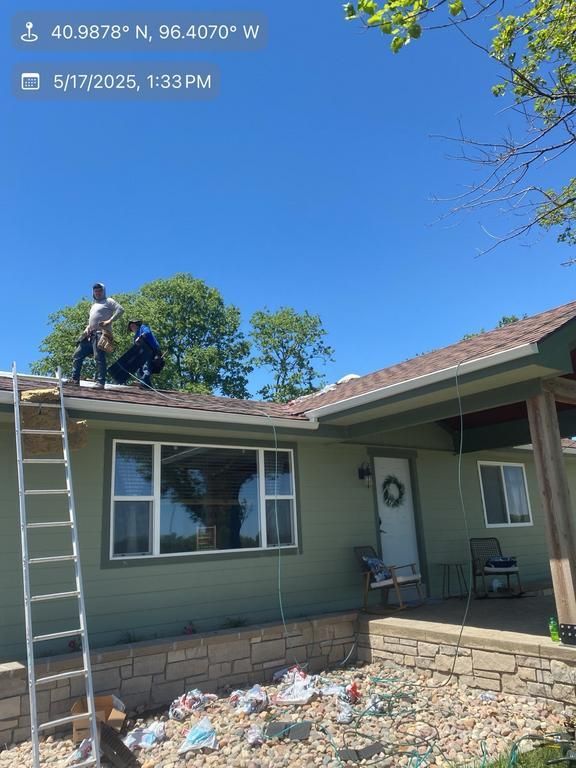A man on a ladder is working on the roof of a house.