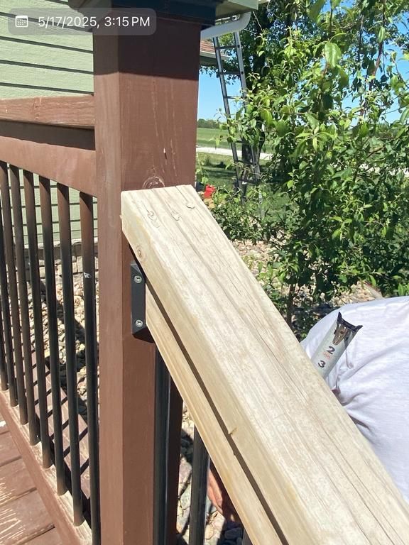 A person is working on a wooden railing on a deck.