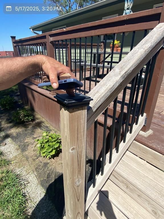 A person is sanding a wooden railing on a deck