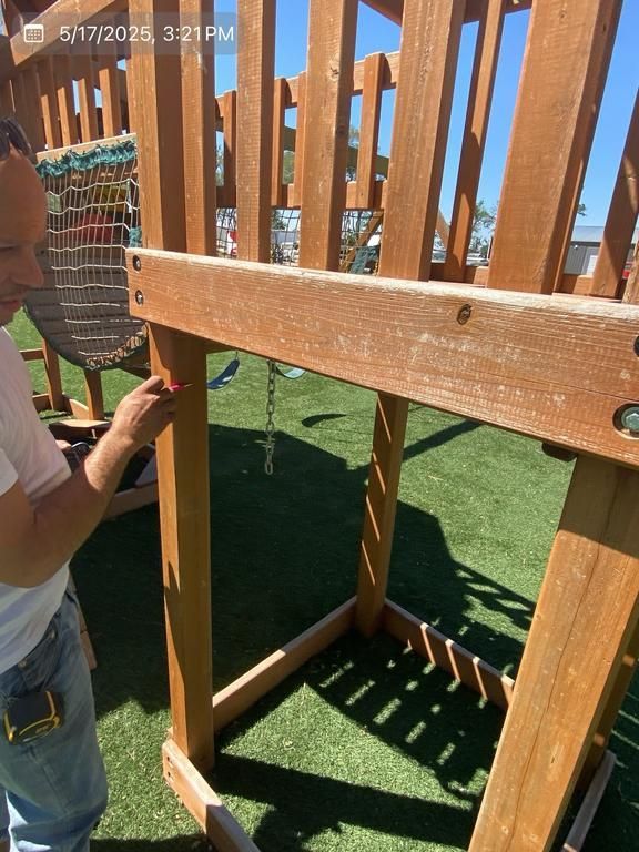 A man is working on a wooden swing set