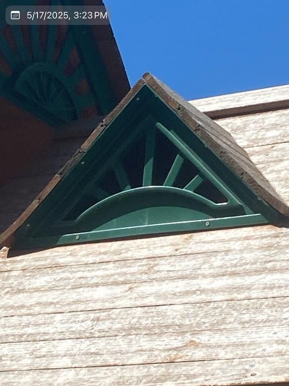 A triangle shaped window on a wooden building