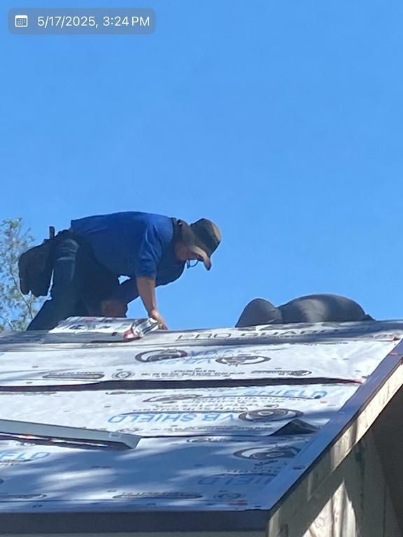 A man in a blue shirt is working on a roof