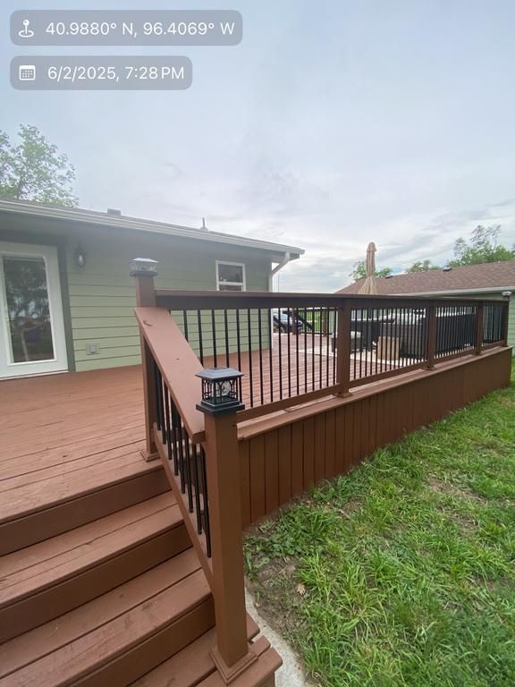 A wooden deck with stairs and a railing in front of a house.