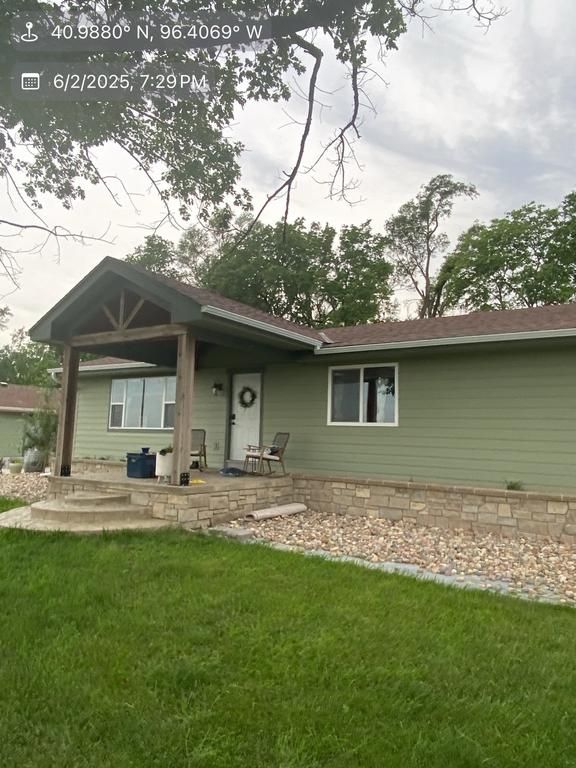 A green house with a brown roof and a porch