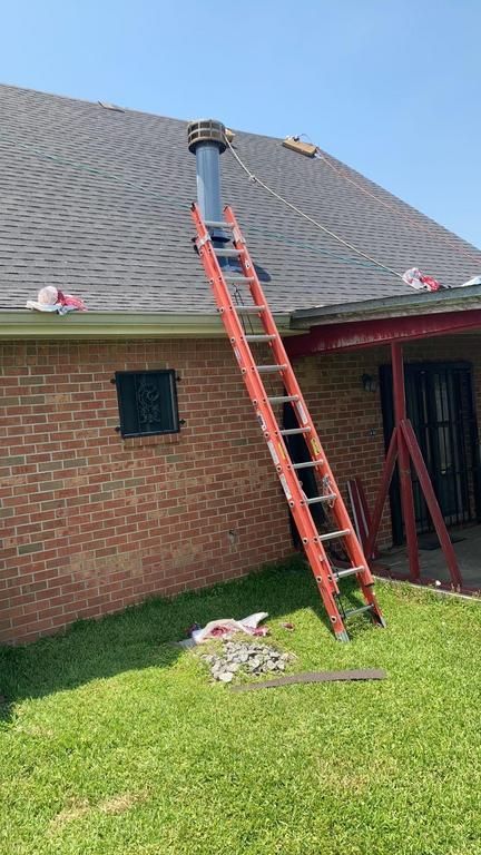 A ladder is leaning against the side of a brick house.