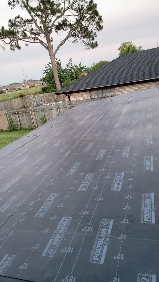 A roof is being installed on a house with a tree in the background.