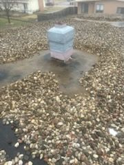 A chimney is sitting on top of a pile of rocks on a roof.