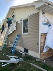 A group of people are working on the side of a house.