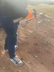 A person is holding a hammer and rake on a wooden deck.