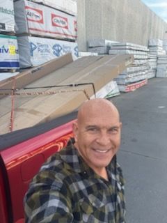 A man in a plaid shirt is standing next to a red truck