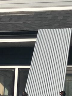 A person is holding a large piece of metal in front of a building.