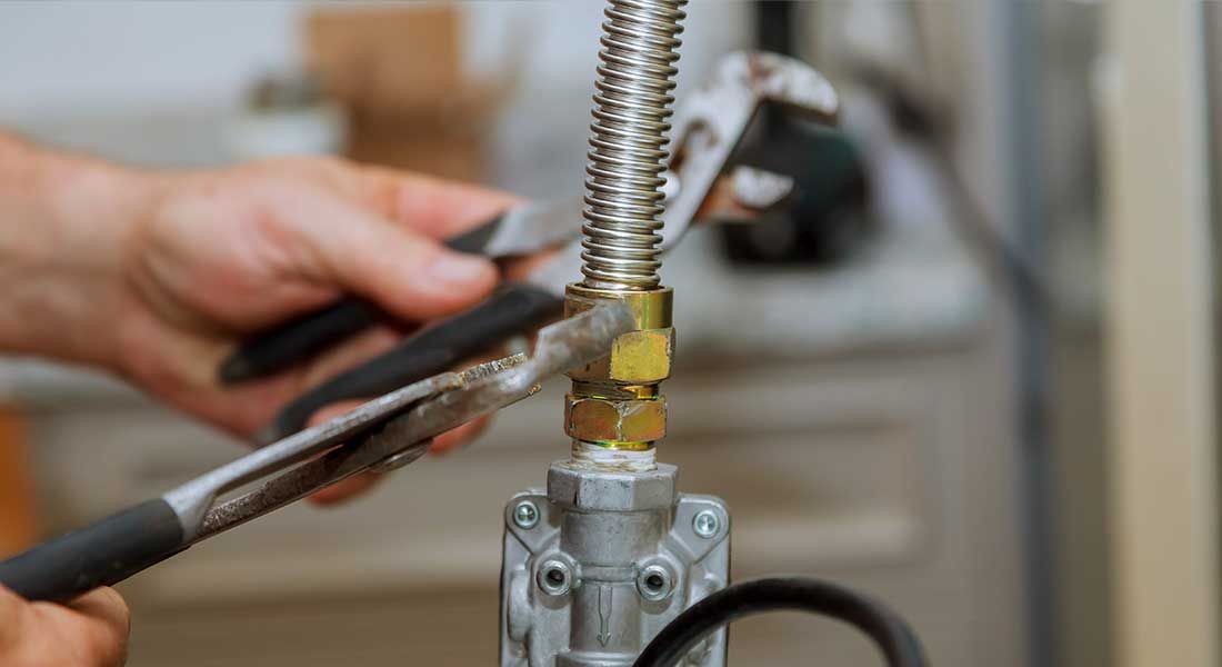 A person is fixing a faucet with a wrench and pliers.