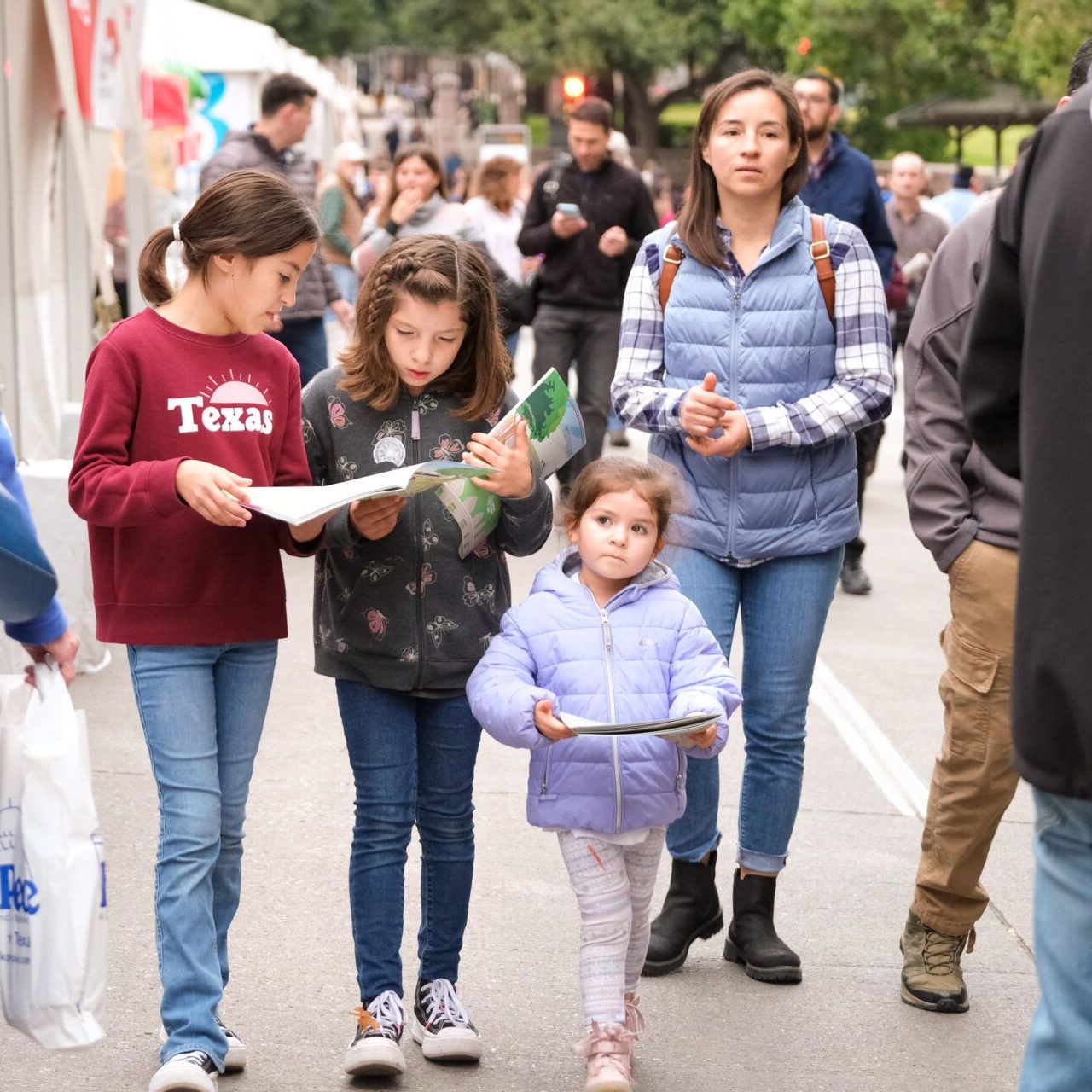 Kids and parents walking and holding books at a festival