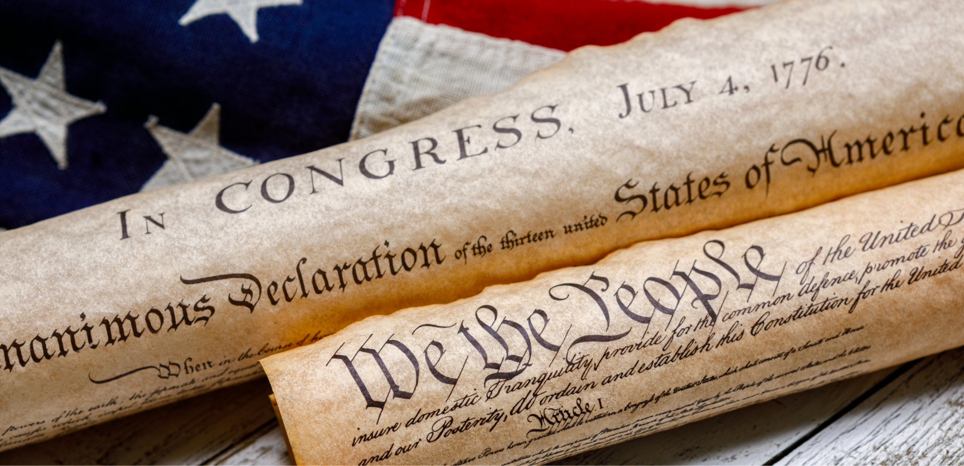 U.S. Constitution and Declaration of Independence parchment on a folded American flag, with stars visible