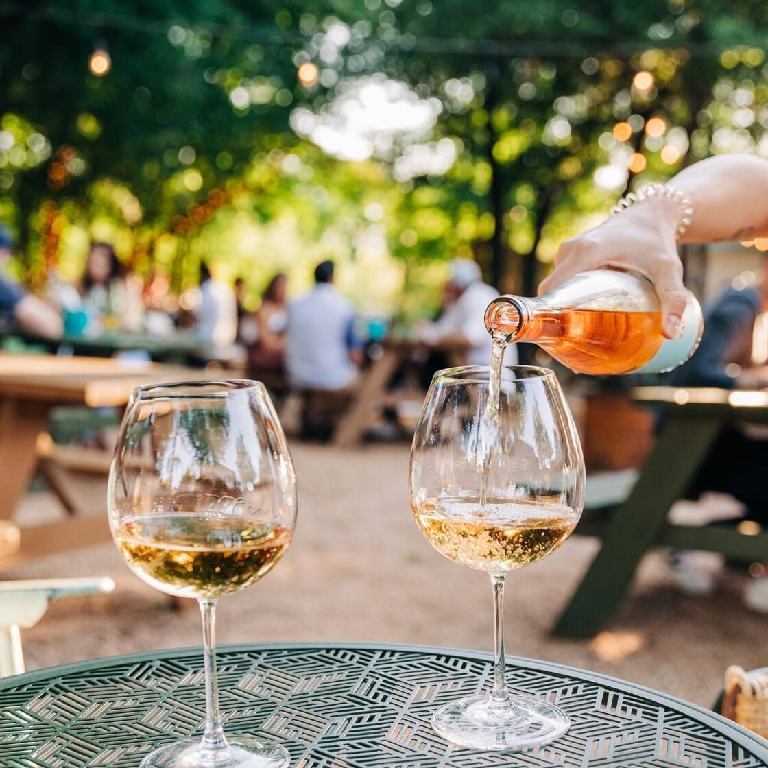 Wine being poured into a glass at an outside venue