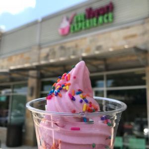 Pink frozen yogurt in a cup, placed in front of a shop