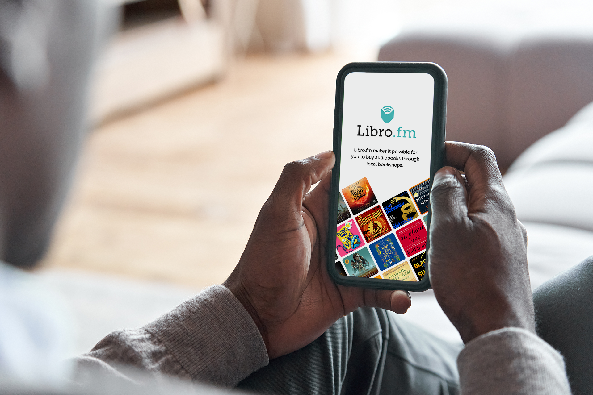 A man is sitting on a couch holding a cell phone in his hands.