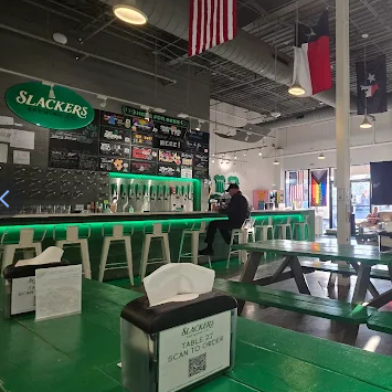 Bar with green accents. Slacker's sign above bar with beer taps. Person sitting at the bar.
