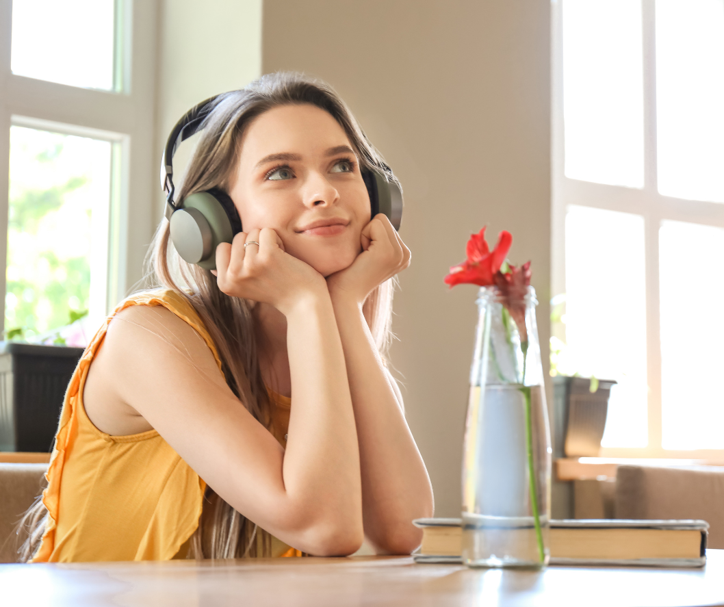 woman wearing headphones, presumably listening to music; she is situated in a well-lit room 