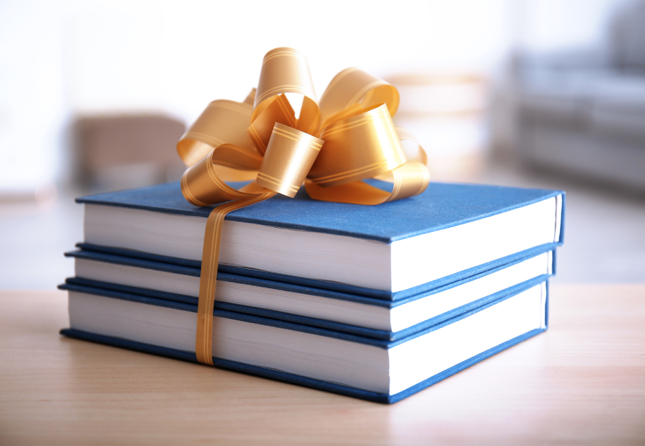 A stack of books with a bow on top of them on a table.