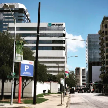 Sunny city street lined with modern office buildings and a parking sign