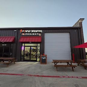 The outside of a brewery with wooden picnic tables