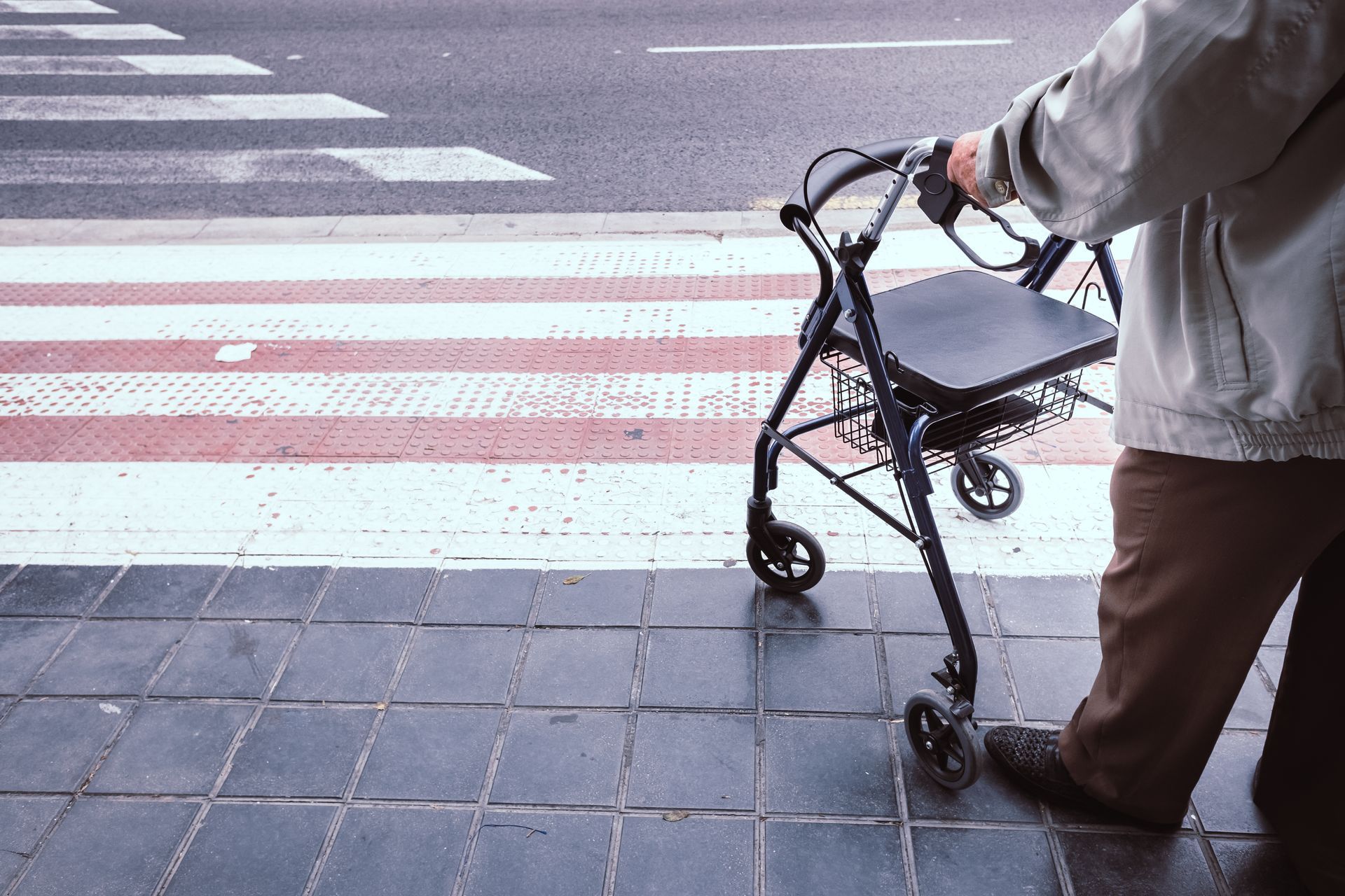 Person with a walker at a crosswalk, preparing to cross the street.