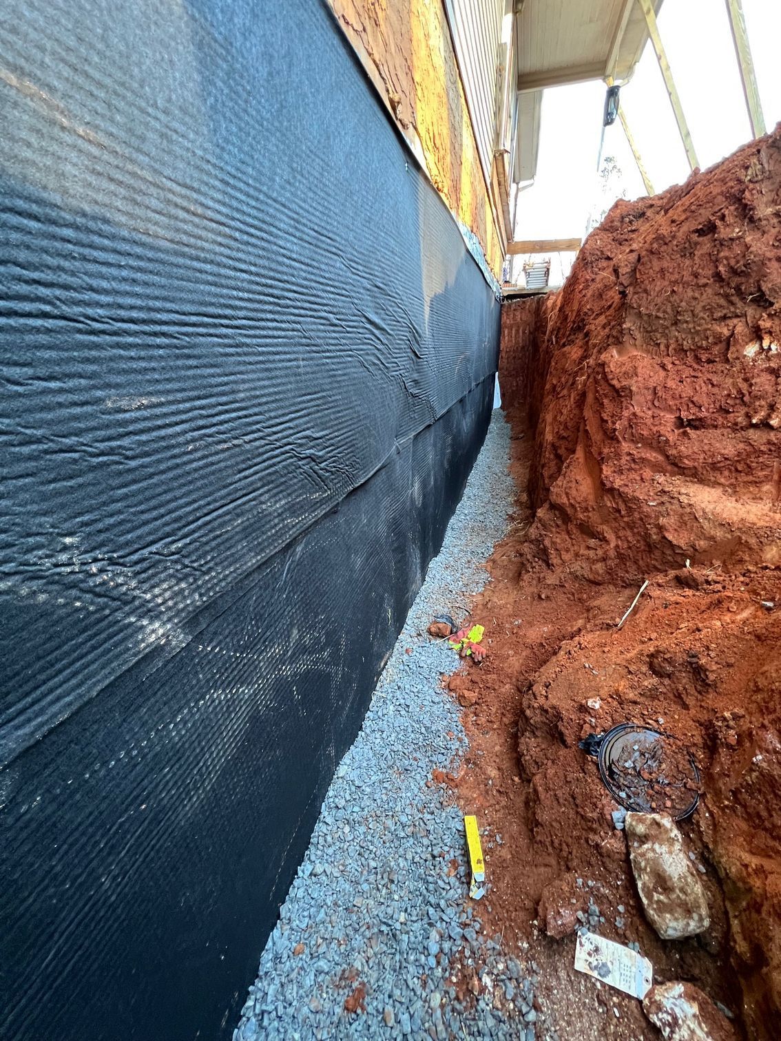 A drainage system is being installed on the side of a house.