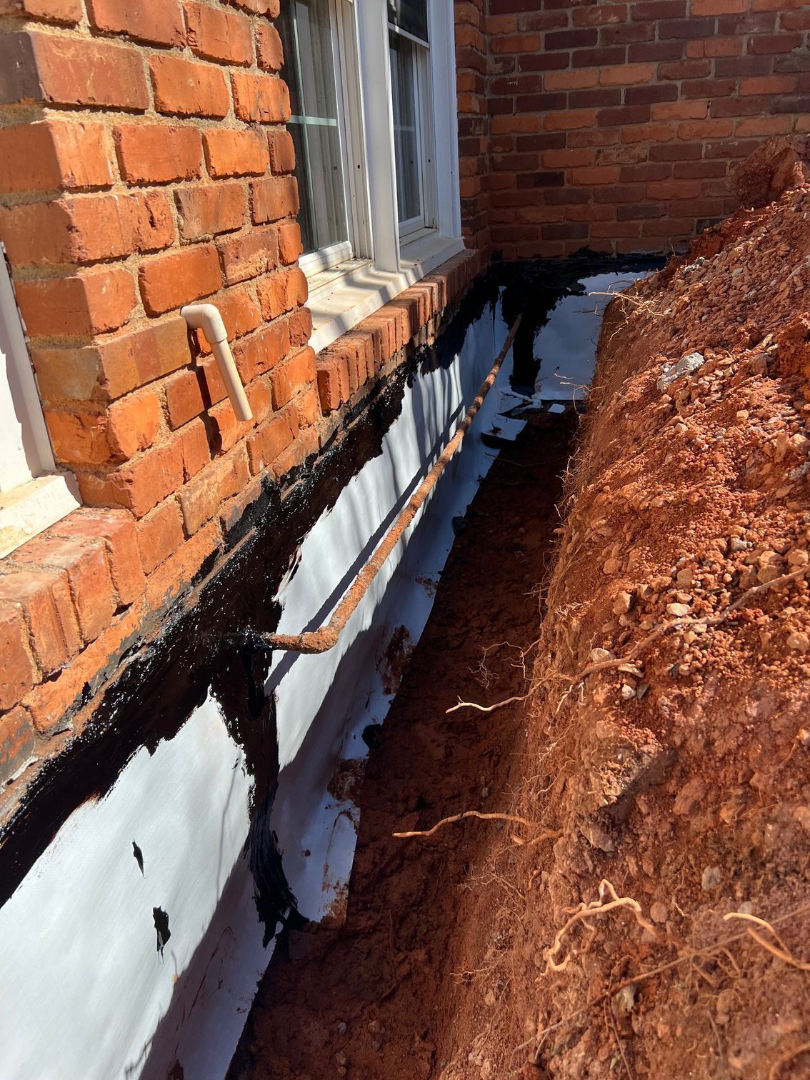 A brick building with a hole in the ground in front of it.