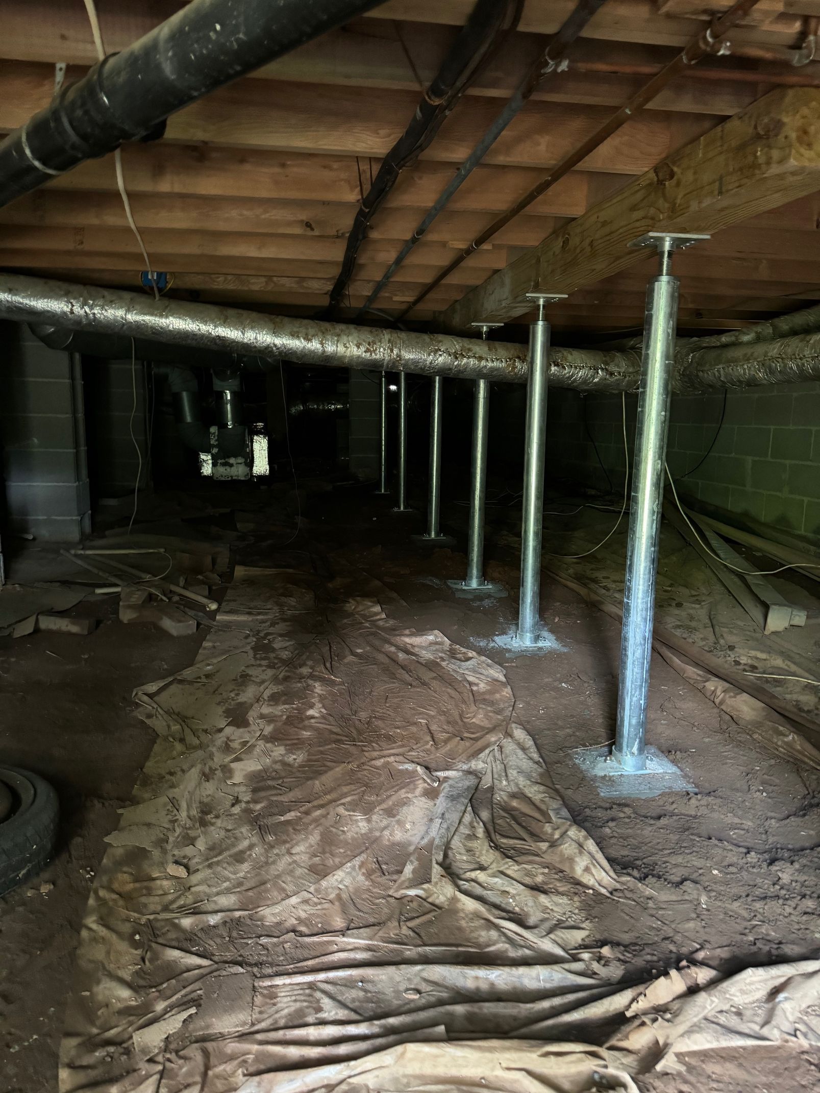A very dark basement with a lot of pipes going through it.