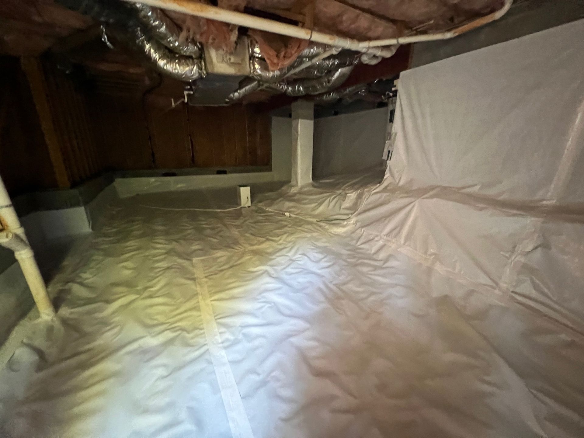 A basement with a lot of white plastic on the floor.