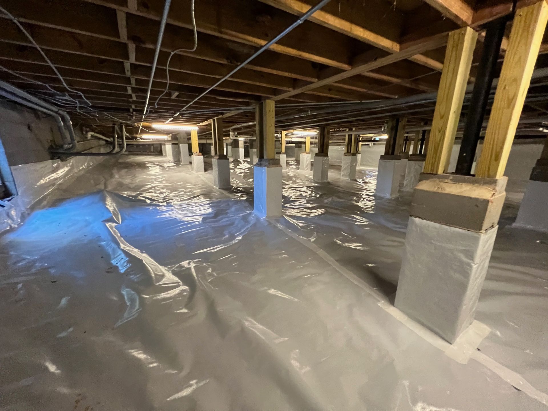 A flooded basement with a lot of plastic on the floor.