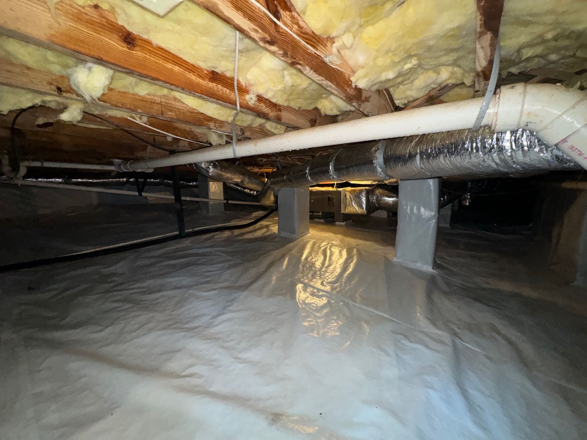 A basement with a lot of pipes and insulation.