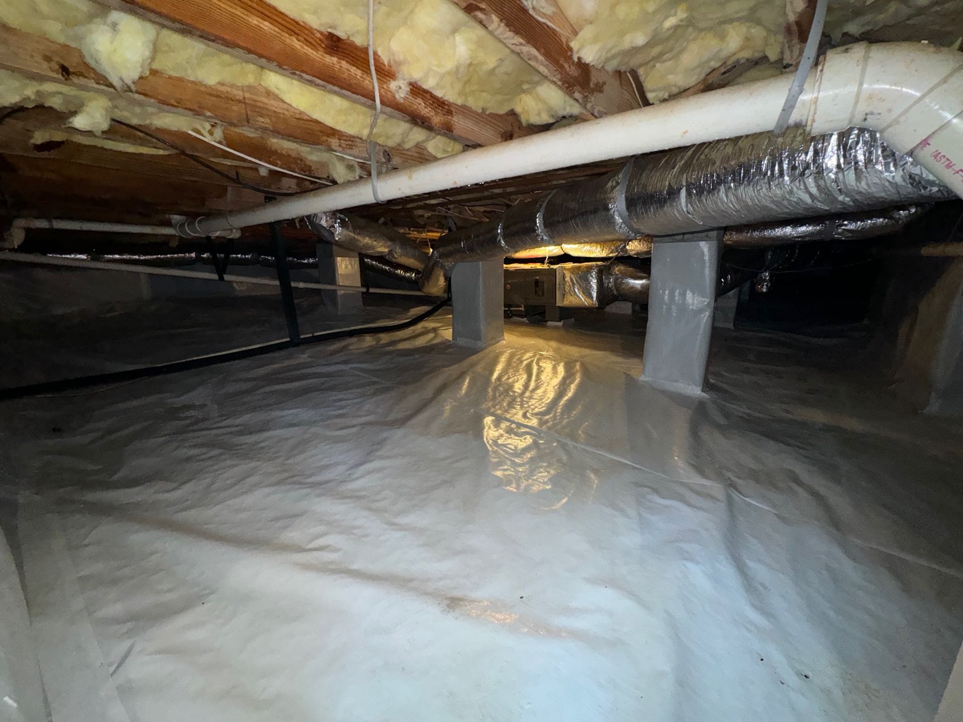 A basement with a lot of pipes and insulation.