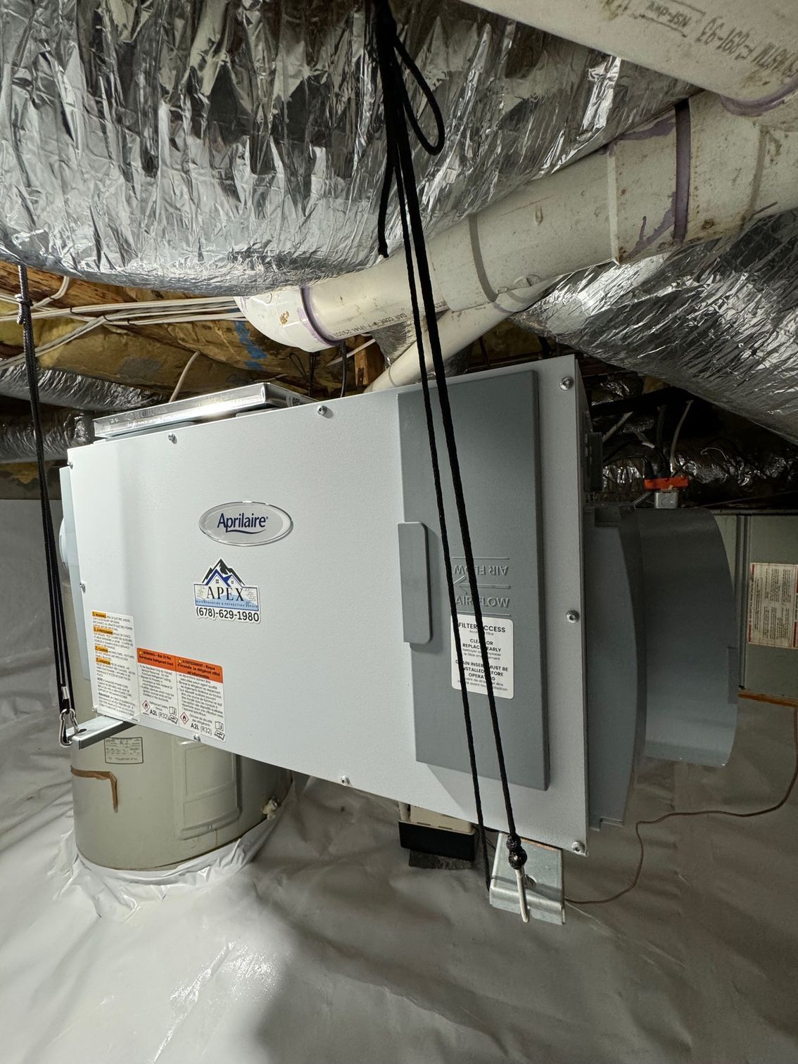 A humidifier is hanging from the ceiling of a basement.