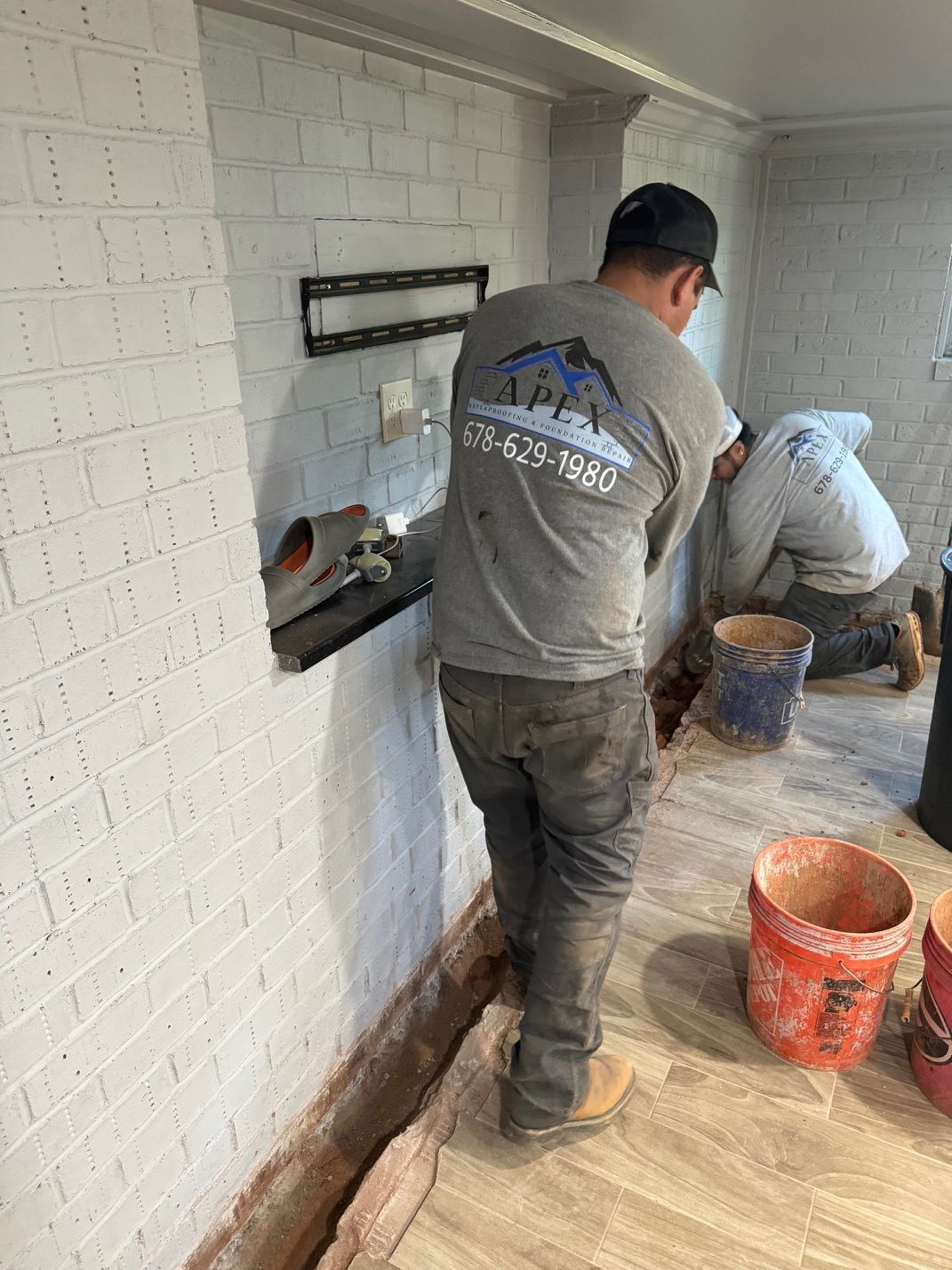 A man is standing in front of a white brick wall.