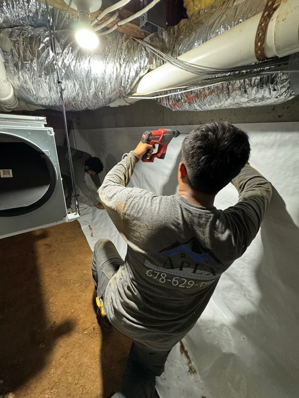 A man is working under a ceiling with a drill.