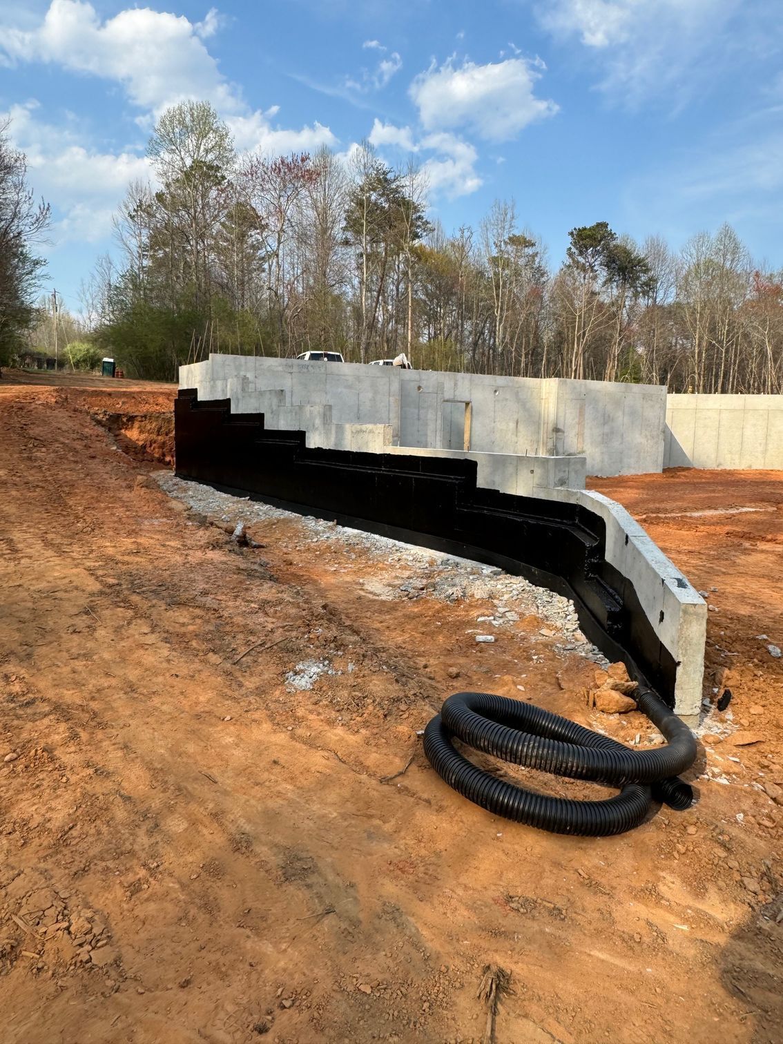 A hose is laying on the ground next to a concrete wall.