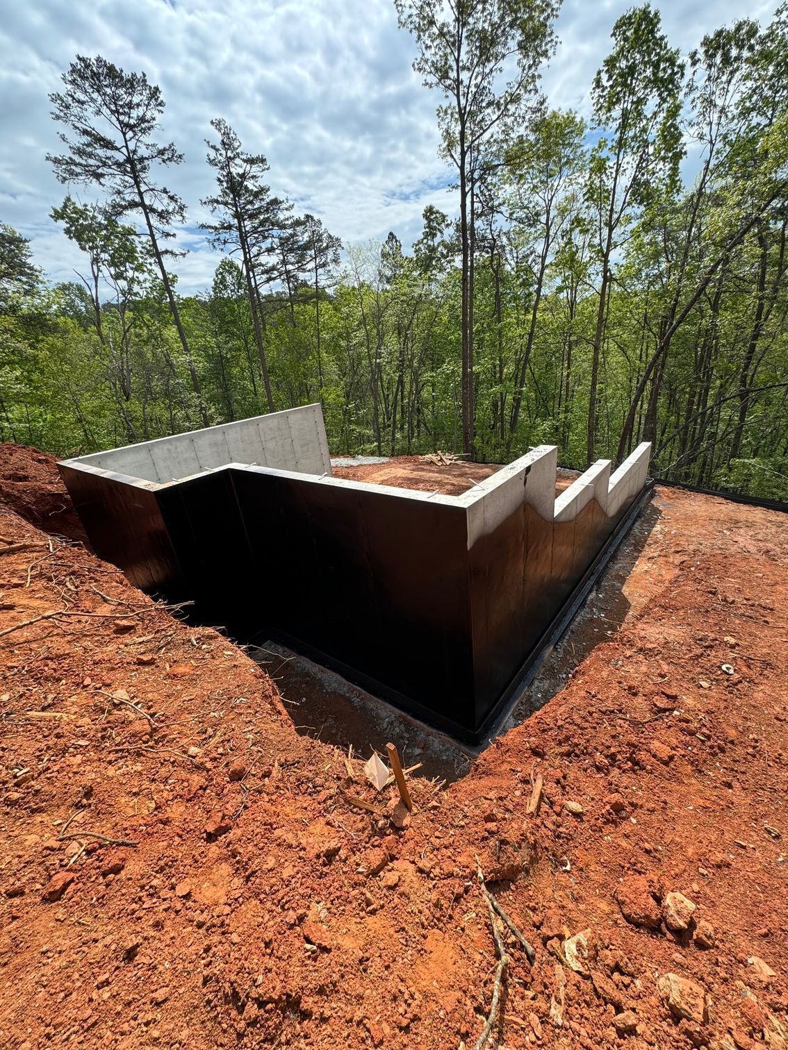 A concrete wall is sitting on top of a dirt hill surrounded by trees.