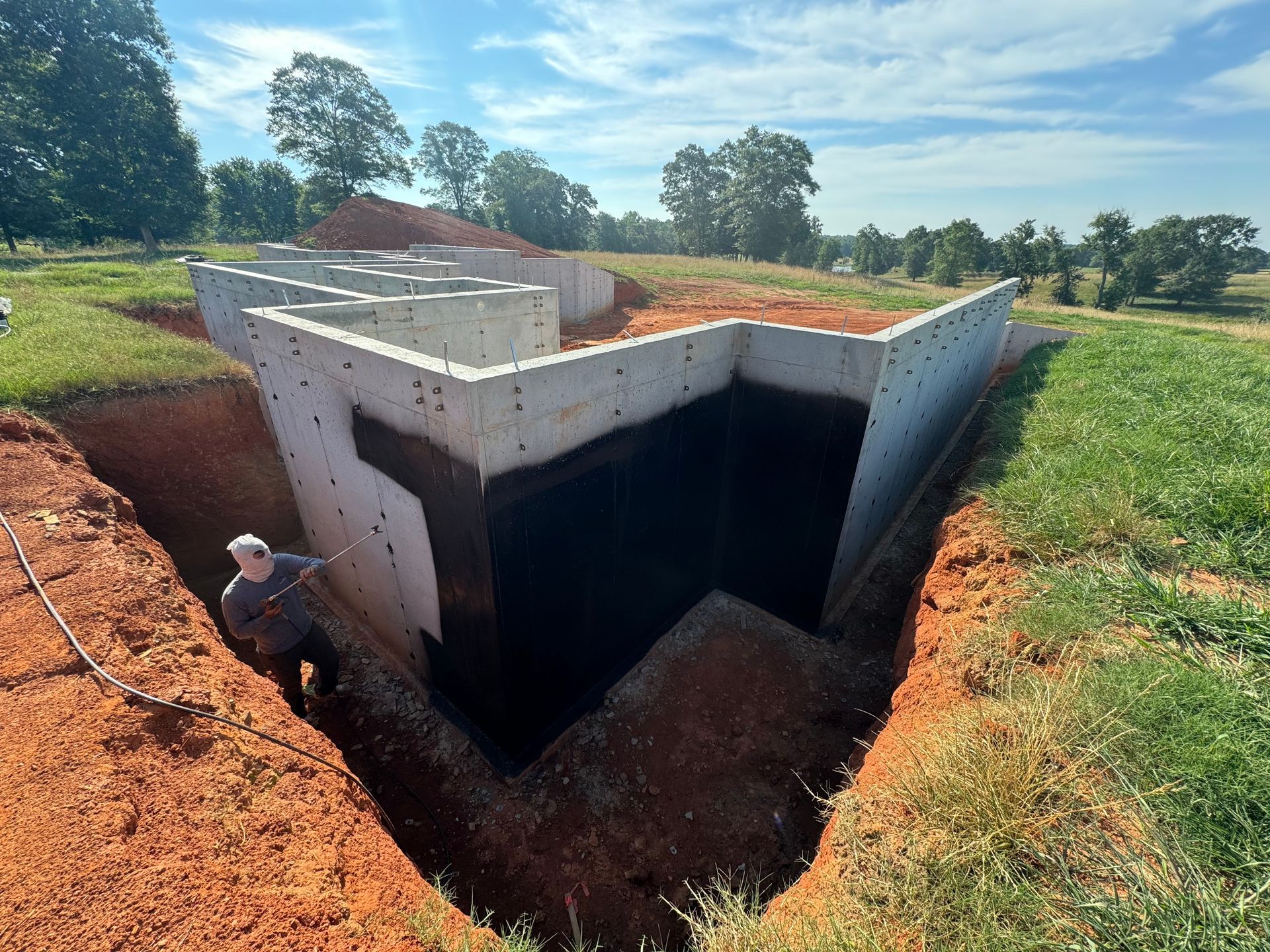 A concrete structure partially buried in red soil, with a person standing inside.
