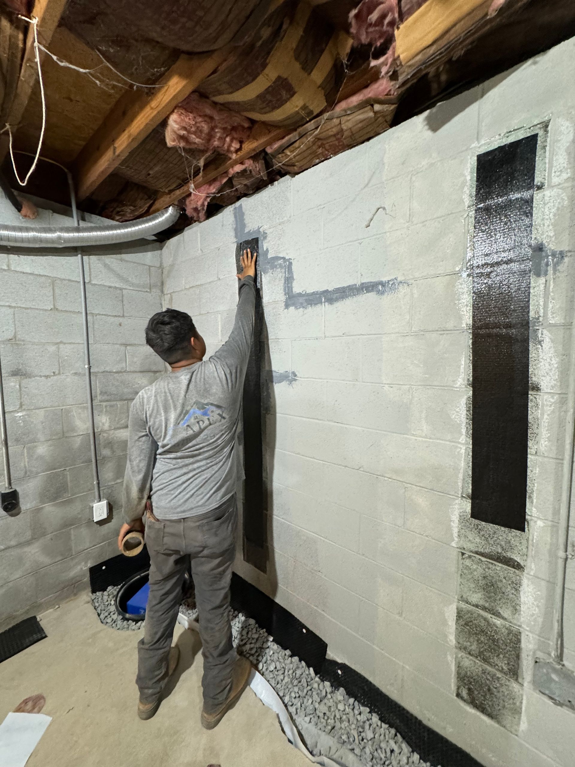 Man applying sealant to a basement wall with carbon fiber reinforcement.