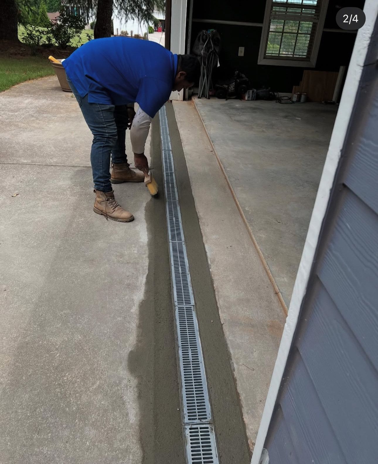Man installs a drainage grate in a concrete driveway.
