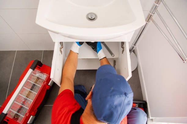 A plumber is finishing the bathroom sink and installing a new drain.