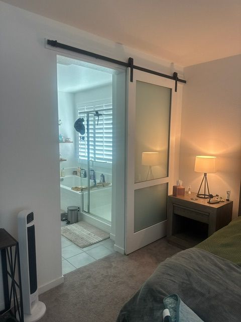 A bedroom with a sliding glass door to a bathroom. The door is closed.