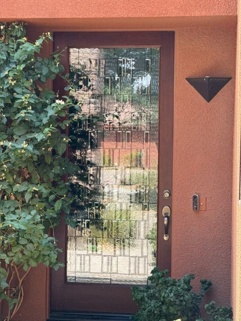 Glass-paneled front door set in a reddish-brown frame, with decorative glass.